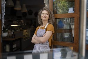 Caucasian waitress standing in apron outside of cafe and looking around